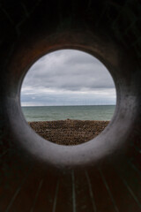 View out to seas and wall of a pier taken thought a hole cut out from a stone sculpture