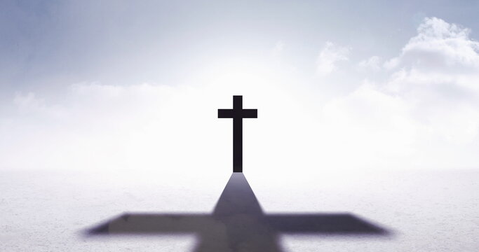 Image of christian cross with shadow over sky with clouds