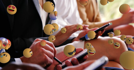 Image of emoticons over hands of caucasian businesspeople with smartphones