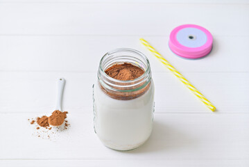 Morning healthy breakfast. Cocoa milk and oatmeal granules. Wooden white background.