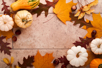Halloween festive autumn background. Autumn decor from pumpkins, berries, maple leaves and chestnuts on old rustic stone tiles backgrounds. Concept of Thanksgiving day Halloween. Top view copy space