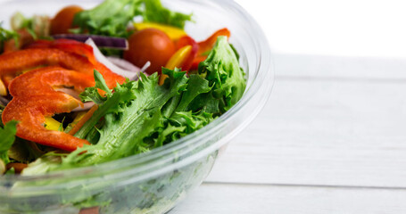 High angle view of fresh vegetable salad in glass bowl over wooden table, copy space