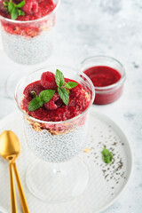 Chia pudding. Healthy vanilla chia pudding in glass with fresh raspberries and mint on white background. Vegan healthy breakfast.