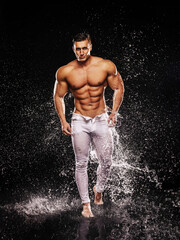 Grinning sexy bodybuilder in white jeans walking on water