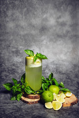cocktail glass with mint and limes on a gray background with copy space
