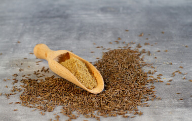 Pile of dry caraway spice with ground caraway powder in wooden spoon. Healthy food cumin spice concept