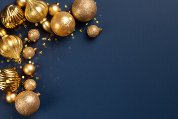 Christmas frame with golden glitter balls and toys on blue background with copy space