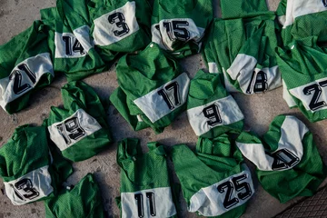 Fotobehang Stockholm, Sweden Numbered green sport team jerseys lay on the ground for use in a grou pactivity. © Alexander