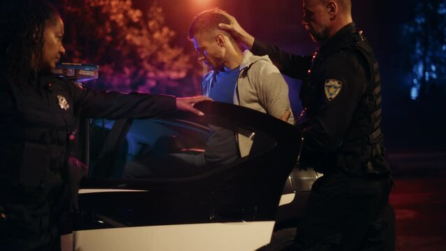 Two Police Officers Arrest Suspect, Put Him in Patrol Сar. Officers of the Law Handcuff Dangerous Criminal on Dark City Street. Cops Arresting Felon, Fight Crime. Cinematic Documentary Slow Motion