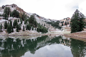 Naklejka premium Volcanic lake in the snowy mountains. Ridge lakes in Lassen Volcanic National Park in California with reflection on the water and mountain peaks in the background