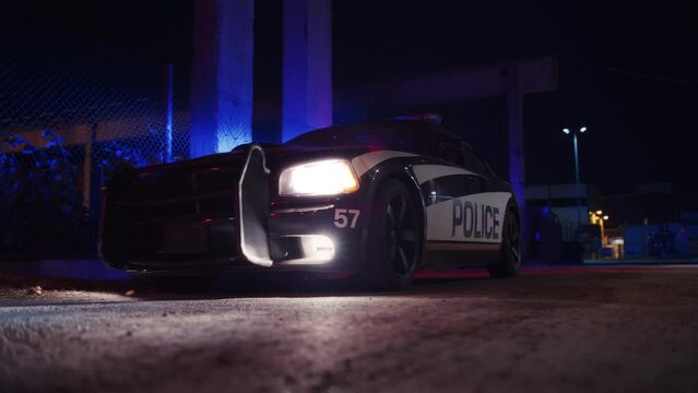 Traffic Patrol Car In Pursuit of Criminal Vehicle, Traffic Stop, Pull Over. Police Officer Gets out of Squad Car, Approaches Suspect. Cinematic Low Ground Angle Shot in Dark Industrial Urban Area
