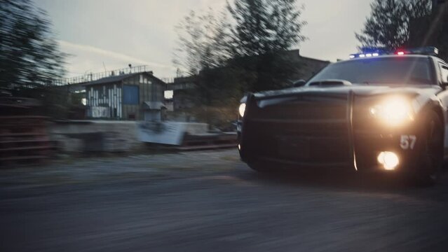 Traffic Patrol Car in Pursuit. Police Officers in Squad Car Chasing Suspect on Industrial Road, Sirens Blazing, High Speed. Cops on Emergency Response Call. Stylish Cinematic Action Packed Shot