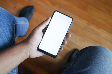 POV shot holding smart phone while sitting on chair 
