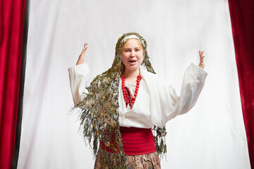 Beautiful smiling girl in stylized slavic red and white national costume on white background