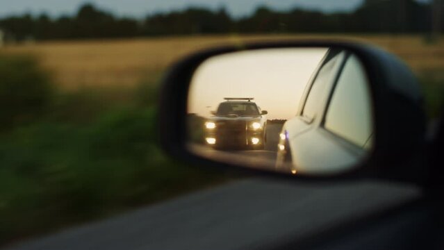 Side Mirror of Criminal Car Chase Shot: Highway Traffic Patrol Car In Pursuit of Suspect Vehicle. Police Officers in Squad Car Chase Felon on Road. Stylish Cinematic Atmospheric High Speed Action