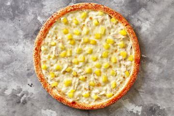 Top view of Hawaiian pizza with cheese sauce, mozzarella, chicken and pineapple on gray background