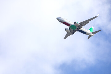 Airplane  in blue sky with light clouds over the house