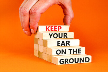 Keep your ear to the ground symbol. Concept words Keep your ear on the ground on wooden blocks. Businessman hand. Beautiful orange background. Business keep your ear on the ground concept. Copy space.
