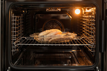 open electric oven with hot air ventilation. New oven. Door is open and light is on. 