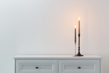 burning candles on white wooden shelf in white interior