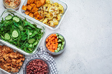 Vegan meal prep containers with  marinated tofu, beans, baked vegetables, green salad and vegetable sticks.