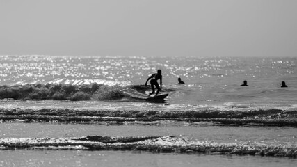 A man is surfing on a surfboard in Agadir beach in black and white
