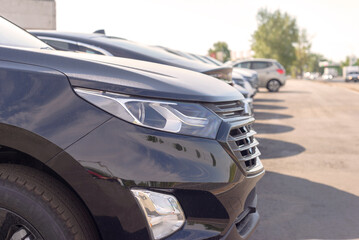 headlamp of the black car in the parking lot at the dealership