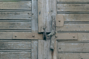 Old weathered wooden barn door with steel hinges