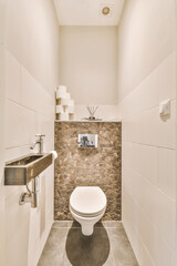 Wall hung toilet and small sink in corner in lavatory room with beige tile