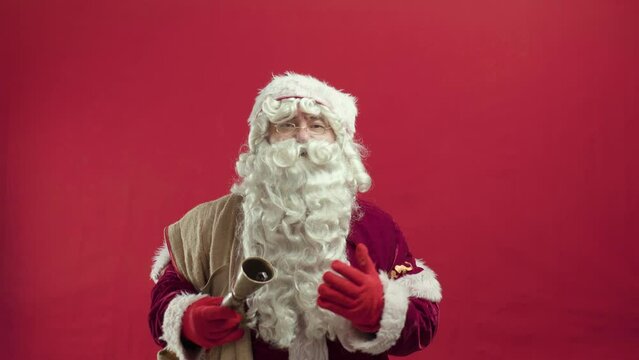 santa claus with bag and ring bell portrait against red background. talking and smiling laughing hohoho