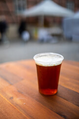 Frisch gezapftes Bier mit weißer Schaumkrone in einem Becher auf einem Holztisch
