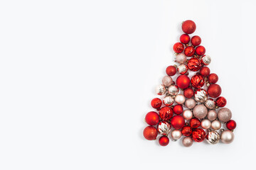 Decorative balls are laid out in the form of a Christmas tree on a white background. Top view, flat lay.