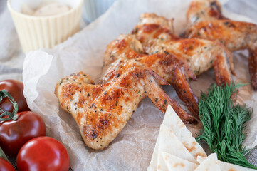 Ready spicy grilled chicken wings with greens and tomato. Summer rest concept