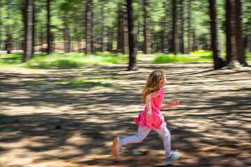 Fototapeta premium A girl running through the forest on a sunny day.