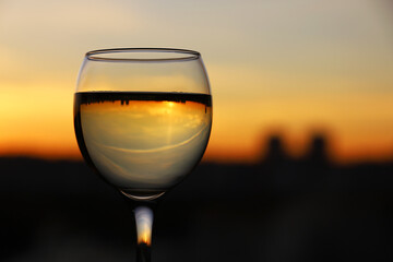Glass with white wine on sunset sky and city background. Concept of celebration, wine industry