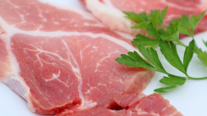 Raw Pork Slice in White Round Plate decorated with parsley. Fresh raw pork.