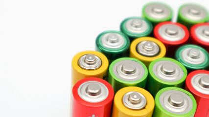 Different colours of batteries on white background. Close up of positive ends batteries, selective...