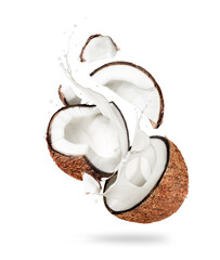 Coconut broken into two halves in the air with splashes of milk