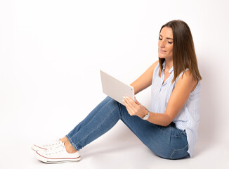 Young woman sitting on the floor using a digital tablet isolated over white background.