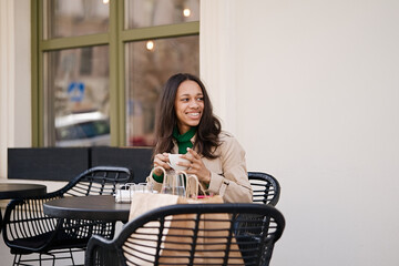 Young smiling african american girl drinking coffee in a cozy cafe. Holidays, lunch time and vacation concept      