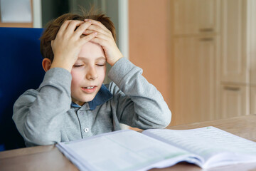 Upset school kid boy making homework during quarantine time from corona pandemic disease. Crying...