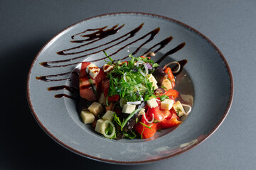 closeup of georgian salad with tomato, cheese and green dill on black background