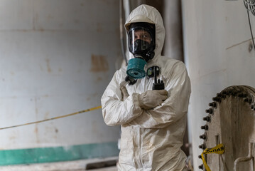 A worker in special chemical protective clothing stands in front of a tank of cyanide.