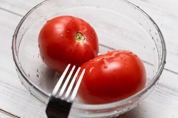 Peeling tomatoes in boiling water. Piercing tomatoes with a fork before pouring hot water.