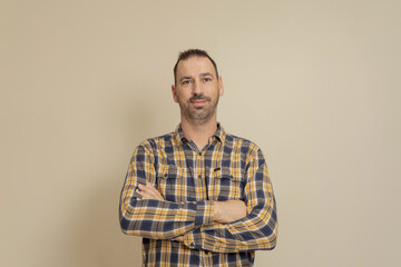 Cheerful confident Caucasian man in checkered shirt with arms crossed on his chest, isolated on beige background. Modern businessman in meeting, online education and presentation, video call.