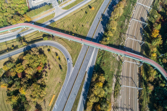 Footbridge with cycle path and pedestrian walkway over a city highway and railway in Krakow, Poland. Aerial view from above © kilhan