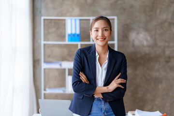 Pretty and confident young Asian business woman standing with her arms crossed and smiling brightly...