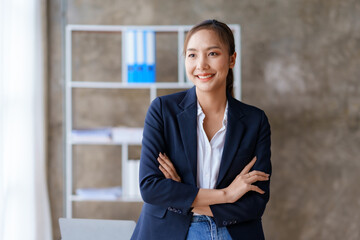 Pretty and confident young Asian business woman standing with her arms crossed and smiling brightly...