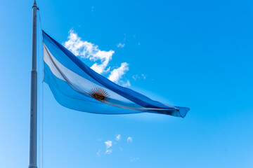Argentine flag flying on a mast against a sunny blue sky. Argentina's national symbol