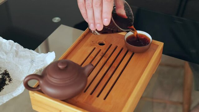 Chinese tea ceremony. Take glassware and pour hot tea into an earthenware bowl. Brewing Chinese tea on a tea board. 4k. slow motion